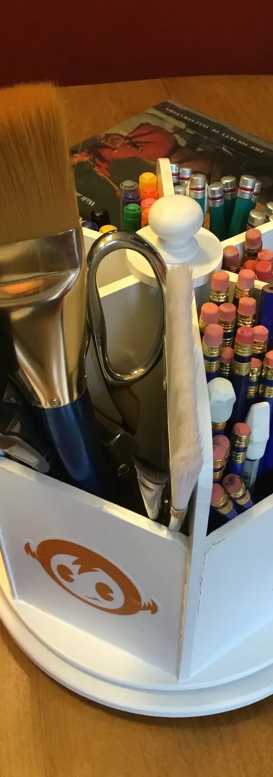 A MentorWings supply caddy full of brushes, pencils and markers